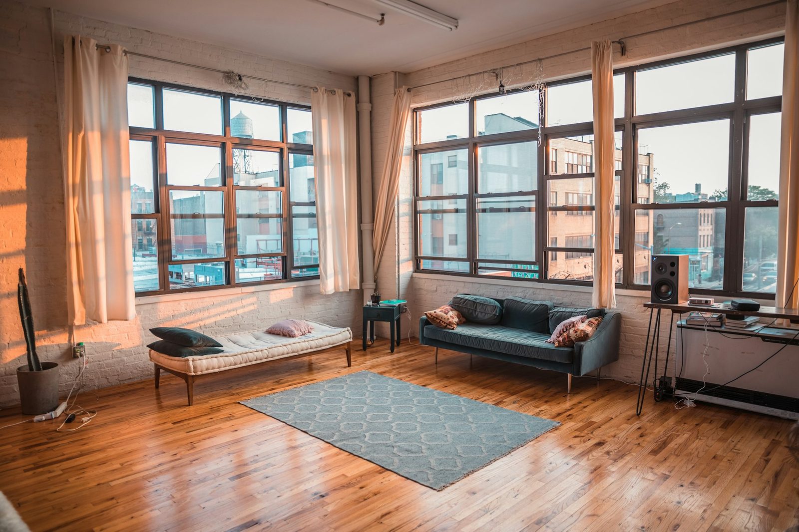Living room with tall wood-framed windows, a daybed, a sofa and a wood floor