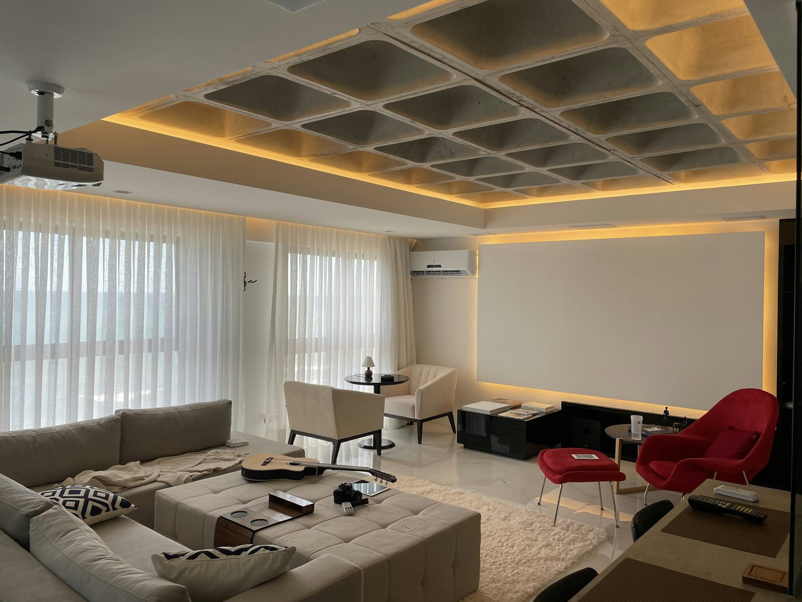 Living area with a large sectional sofa, two red chairs and sheer curtains