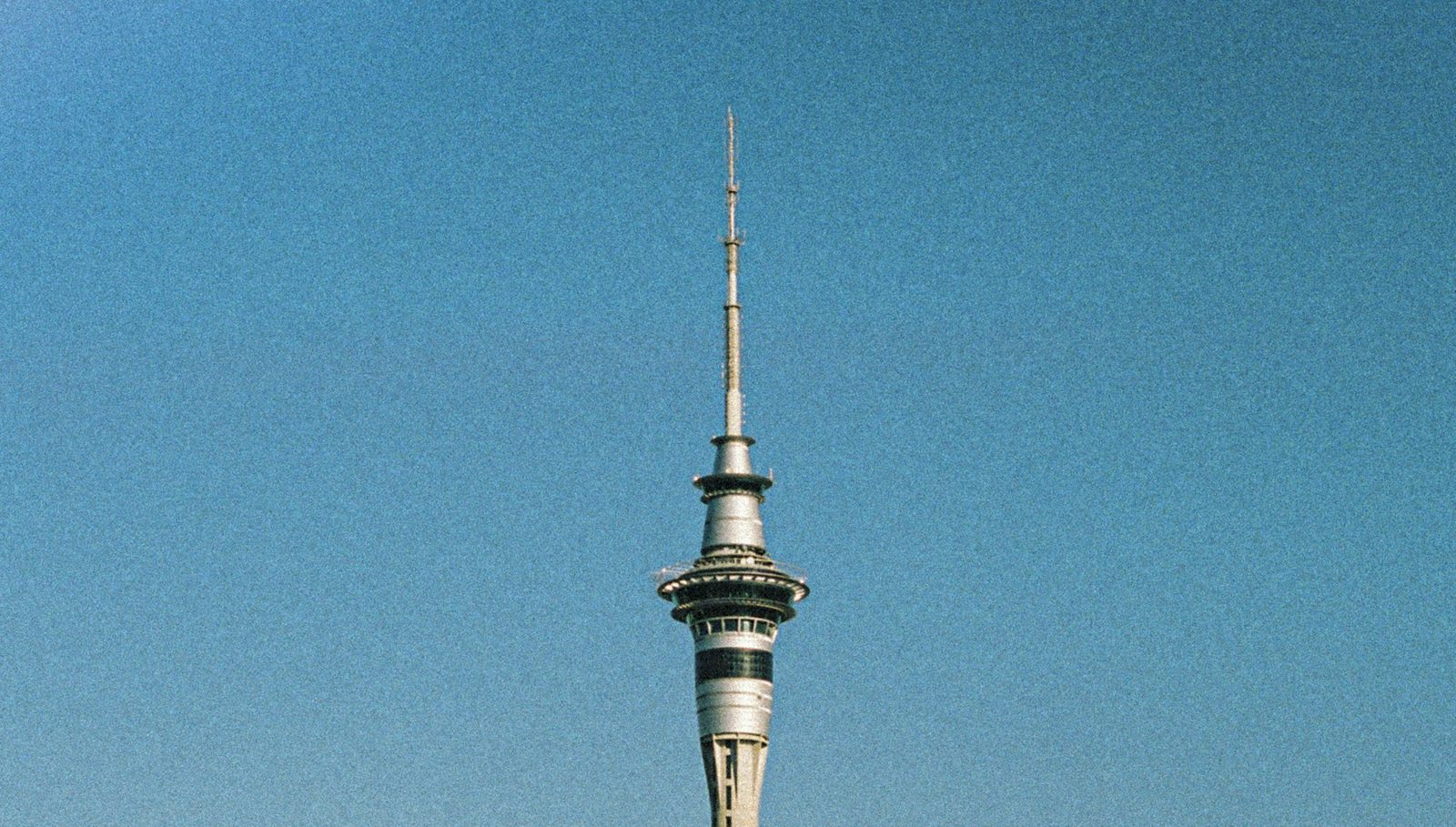 The Sky Tower against a blue sky, rising above city buildings and the waterfront